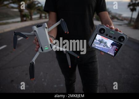 Tenerife, Spagna, 27th gennaio 2023: Un pilota di droni che tiene il nuovo drone DJI mini 3 Pro e il suo telecomando con schermo Foto Stock