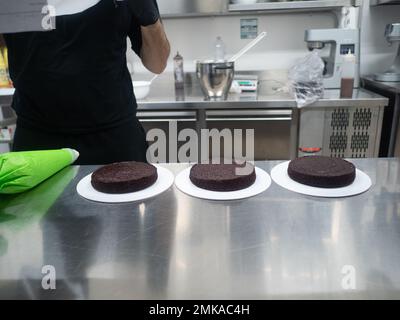 chef pasticceria designer confettando una torta al 3° piano satinata farcita con fragole, mirtilli e panna montata al burro. Struttura torta bef Foto Stock