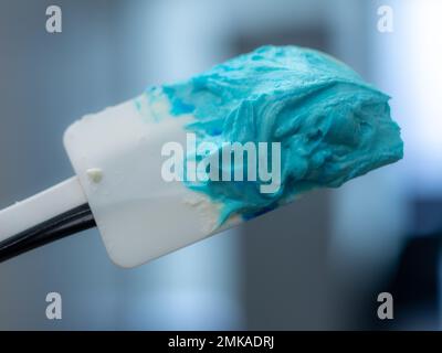 riempimento tubature di glassa turchese per la decorazione di torte smerigliate in laboratorio di cucina Foto Stock