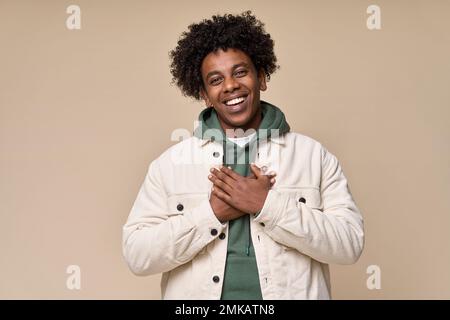 Felice grato teen africano tenendo le mani sul petto esprimendo gratitudine. Foto Stock