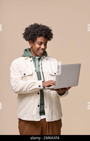 Sorridente studente afro-americano utilizzando un computer portatile isolato su sfondo beige. Foto Stock