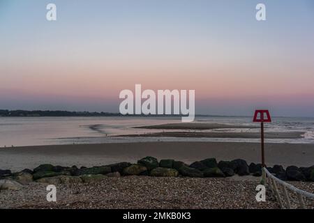 Tramonto dal cielo rosa sul banco di sabbia di Mudeford con vista verso Christchurch Bay durante la bassa marea, Hengistbury Head, Dorset, Inghilterra, Regno Unito Foto Stock