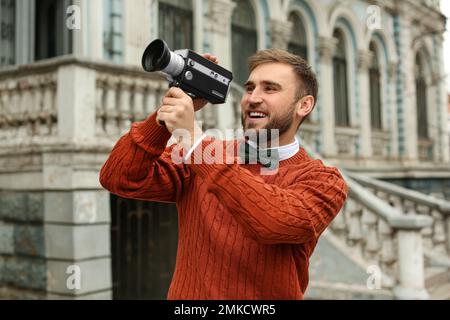 Giovane uomo con videocamera vintage all'aperto Foto Stock