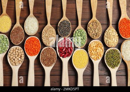 Composizione piatta con diversi tipi di legumi e cereali su tavola di legno. Grani organici Foto Stock