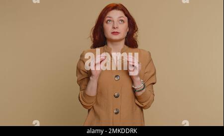 Donna arrhead esausta stanca toglie gli occhiali, sente dolore agli occhi, essendo burnout overwork da lunghe ore di lavoro, mal di testa. Infelice ragazza zenzero triste giovane isolato da solo su sfondo beige studio Foto Stock