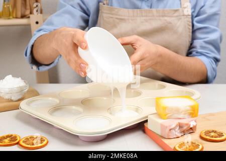 Donna che fa sapone naturale fatto a mano a tavola bianca, primo piano Foto Stock