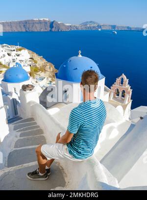 I giovani turisti visitano Oia Santorini Grecia in una giornata di sole durante l'estate con case e chiese imbiancate, l'isola greca Cicladi del Mar Egeo Foto Stock