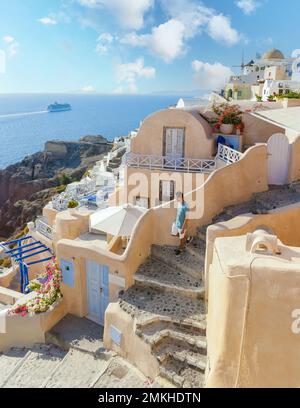 I giovani turisti visitano Oia Santorini Grecia in una giornata di sole durante l'estate con case e chiese imbiancate, l'isola greca Cicladi del Mar Egeo Foto Stock