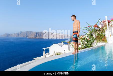 Uomini che si rilassano in una piscina infinity durante le vacanze a Santorini, piscina che si affaccia sul mare Caldera di Santorini, Oia Grecia, Grecia isola greca Cicladi vacanza di lusso. Foto Stock