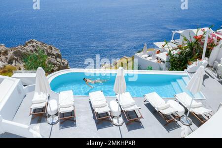 Uomini che si rilassano in una piscina infinity durante le vacanze a Santorini, piscina che si affaccia sul mare Caldera di Santorini, Oia Grecia, Grecia isola greca Cicladi vacanza di lusso. Foto Stock