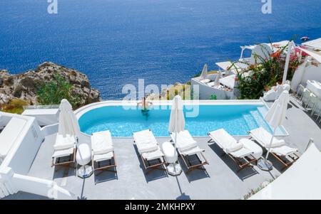 Uomini che si rilassano in una piscina infinity durante le vacanze a Santorini, piscina che si affaccia sul mare Caldera di Santorini, Oia Grecia, Grecia isola greca Cicladi vacanza di lusso. Foto Stock