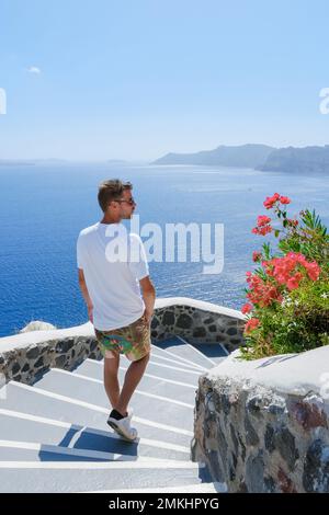 I giovani turisti visitano Oia Santorini Grecia in una giornata di sole durante l'estate con case e chiese imbiancate, l'isola greca Cicladi del Mar Egeo Foto Stock