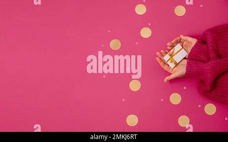 Buono regalo da donna su sfondo rosso con cordoncini dorati a forma di stella e tondo. Concetto di auguri di Natale Foto Stock