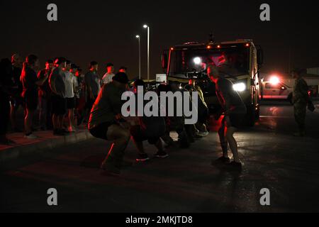 I membri dello Squadrone delle forze di sicurezza esterne del 380th tirano un camion dei vigili del fuoco durante il concorso Battaglia dei distintivi, 9 settembre 2022, presso la base aerea di al Dhafra, negli Emirati Arabi Uniti. Molte gare di Battaglia dei distintivi si svolgono a livello nazionale, come gare atletiche annuali tra polizia locale e vigili del fuoco. Foto Stock