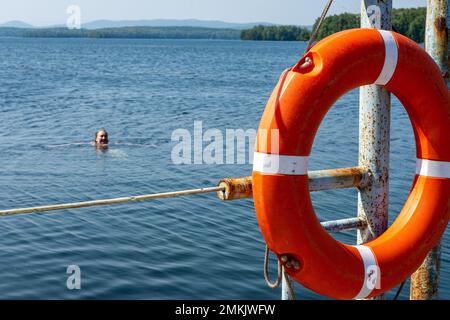 Lifebuoy appeso alla maniglia del molo. Il concetto di risparmio annegando sull'acqua. Foto Stock