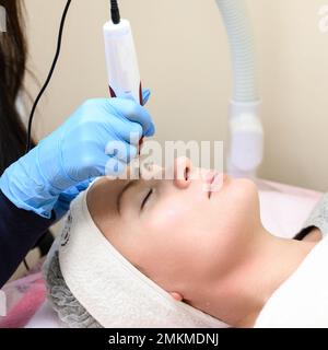 Un cosmetologo esegue una procedura di ringiovanimento mesoterapico con l'aiuto di dermapen, una visita ad un cosmetologo. Foto Stock