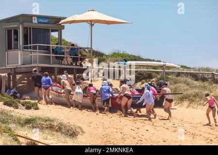 Sydney Northern Beaches Surfboat carnevale a North Narrabeen Beach, gli equipaggi di Surfboat rimuovono il Surfboat dalla spiaggia utilizzando i parafanghi per barche a rolling boat Foto Stock