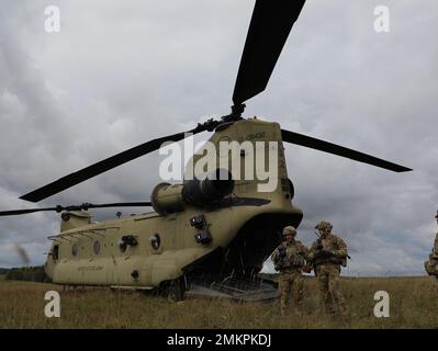 Sgt. Dell'esercito degli Stati Uniti 1st Classe José Zarate (a destra) un osservatore-controllore-trainer assegnato al comando di addestramento dell'esercito 7th istruisce il Chief Warrant Officer 2 Austin Reidy (a sinistra) e Sgt. Matthew Cullen (centro) con il 214th Aviation Regiment, sulla formazione medica di evacuazione di fronte a un elicottero CH-47 Chinook durante Saber Junction 22 presso il Joint Multinational Readiness Center, Hohenfels, Germania, 11 settembre 2022. Saber Junction 22 è un esercizio di rotazione multinazionale progettato per valutare la prontezza della Brigata Airborne 173d dell'esercito degli Stati Uniti ad eseguire operazioni unificate e in un comune, Comb Foto Stock