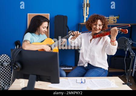 Due musicisti femminili suonano chitarra classica e violino nello studio musicale Foto Stock