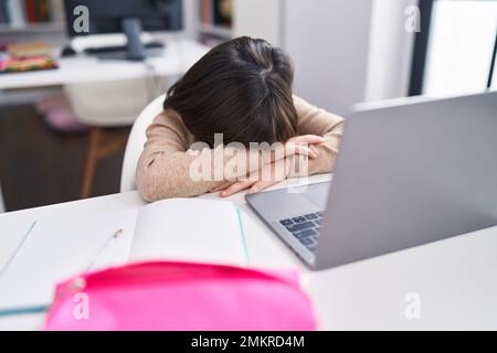 Adorabile ragazza ispanica studente stressato appoggiarsi sul libro in classe Foto Stock