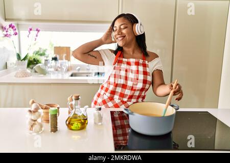 Donna ispanica bruna cucina indossando cuffie in cucina Foto Stock
