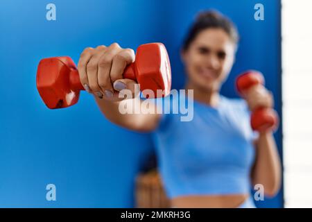 Giovane donna latina che indossa abbigliamento sportivo boxing con manubri al centro sportivo Foto Stock