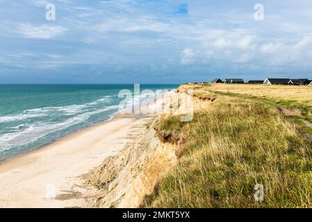 Danimarca, Nord Jutland, Lönstrup: Case vacanze nelle dune sopra le scogliere e il mare della baia di Jammer in sole con cielo nuvoloso Foto Stock