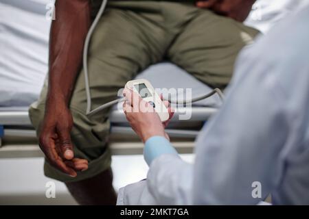 Immagine ravvicinata del medico che misura la pressione sanguigna dell'uomo militare Foto Stock