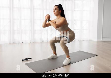 Giovane donna motivata che fa l'allenamento a casa Foto Stock