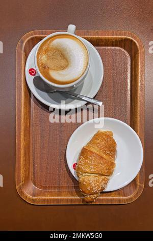 Una tipica colazione italiana: Cappuccino e brioche (croissant) Foto Stock