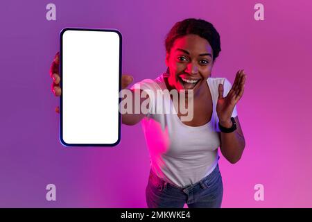 Offerta straordinaria. Excited Black Woman che mostra uno smartphone vuoto alla fotocamera Foto Stock