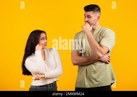 Giovane donna e ragazzo arabo pensivo in casual pensare insieme, isolato su sfondo giallo, studio Foto Stock