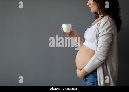 Alimenti per latticini durante la gravidanza. Giovane donna incinta che tiene un bicchiere di latte Foto Stock