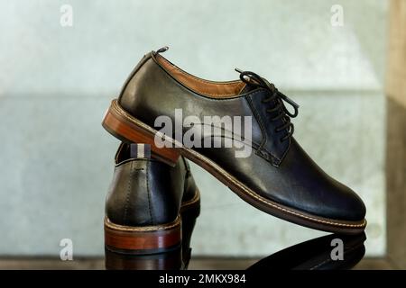 Scarpe in elegante pelle nera allacciate su un pavimento nero. Scarpe formali uomo Foto Stock