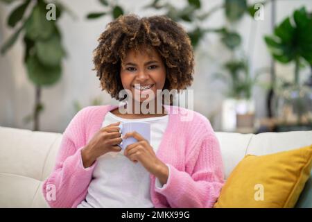 Ritratto di giovane donna che si gusta un caffè aromatico fresco a casa Foto Stock