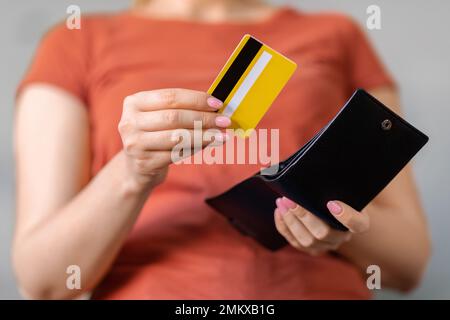 Donna irriconoscibile che tette la carta di credito bancaria dal portafoglio in pelle Foto Stock