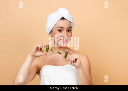 Bella giovane donna indiana che tiene Greenstone Jade rullo facciale per la cura della pelle Foto Stock