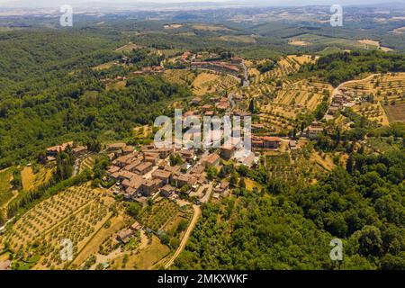 Fotografia di droni di una piccola cittadina rurale circondata da campi agricoli, vigneti e ulivi durante il giorno estivo Foto Stock