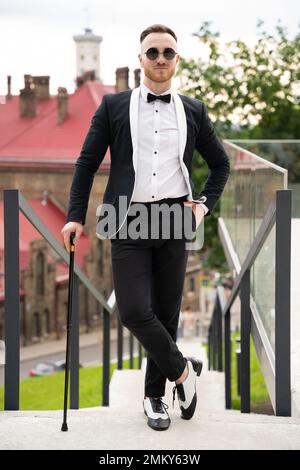 bel ragazzo alla moda vestito in stile retrò con occhiali e canna da zucchero Foto Stock