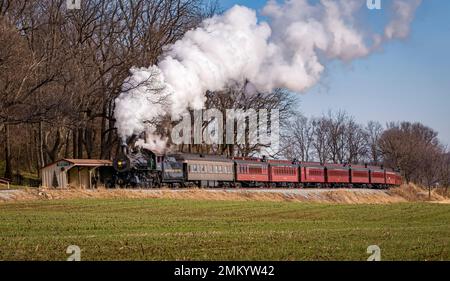 Ronks, Pennsylvania, 4 dicembre 2022 - una vista di un classico treno passeggeri a vapore, che soffia un sacco di fumo e vapore, mentre si viaggia in campagna in un giorno d'autunno Foto Stock