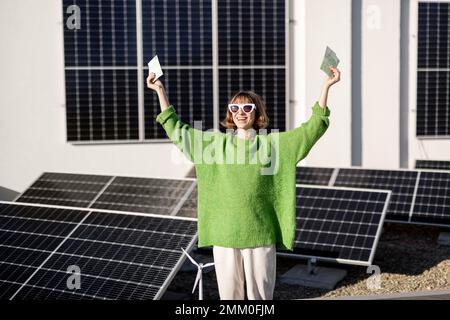 Felice proprietario della famiglia con soldi vicino alla centrale solare Foto Stock
