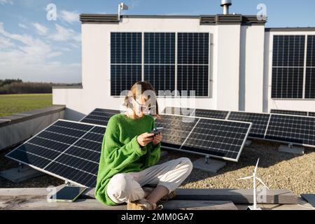 Donna sul tetto della sua casa con una pianta solare Foto Stock