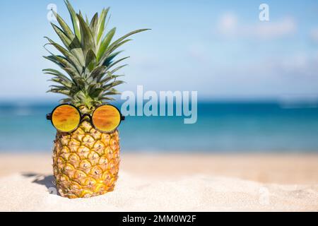 Ananas sulla spiaggia con cielo blu e sfondo mare Foto Stock