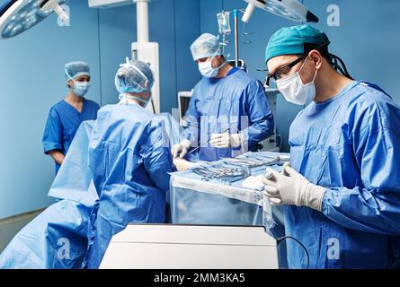 Team medico chirurgico che esegue interventi chirurgici in una moderna sala operatoria Foto Stock