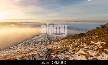 Guardando giù il muro di pietra verso dal sentiero finale alla cima del monte Pen-y-ghent all'alba con nebbia e neve nello Yorkshire Dales Nat Foto Stock