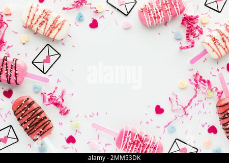 Collage flatlay di cakesicles di San Valentino e decorazioni assortite in un bordo. Foto Stock