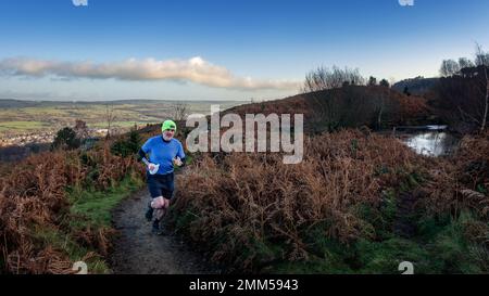 Corridore caduto maschio che indossa pantaloncini corti e un cappello da giorno su un sentiero su Ilkley Moor vicino a uno stagno, West Yorkshire, Inghilterra, Regno Unito Foto Stock