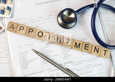 Parola appuntamento raccolto da cubi di legno su documenti medici con stetoscopio e pillole. Foto Stock