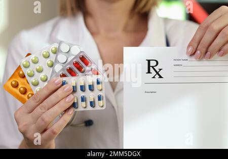Il medico femminile mostra diverse pillole mediche e carta da prescrizione. Foto Stock