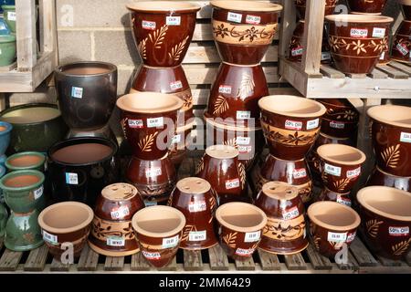 Una grande pila di vasi di ceramica marrone scuro per piantare in un centro giardino a prezzi di vendita Foto Stock